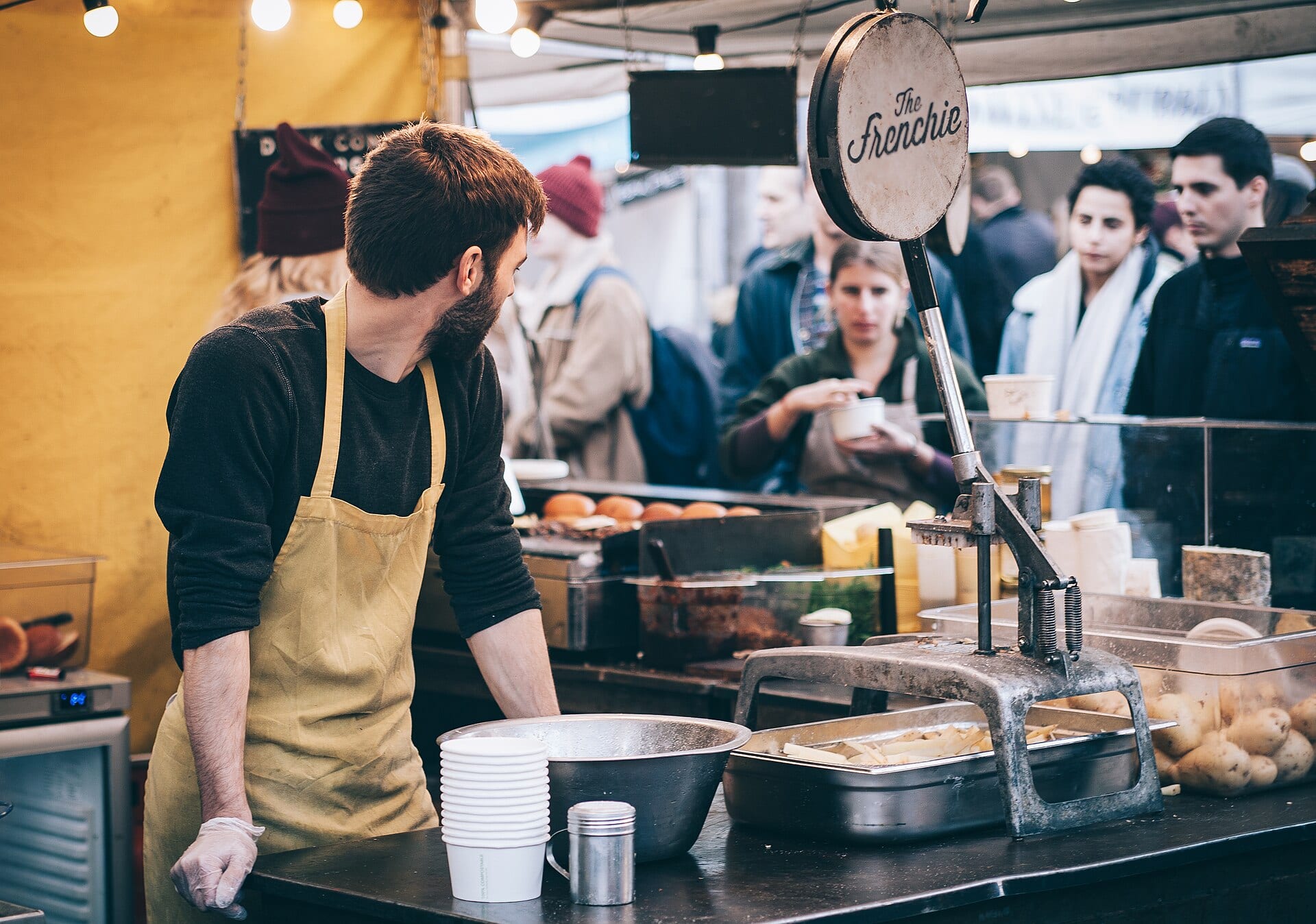 Cuisinier derrière un stand de street food avec des clients