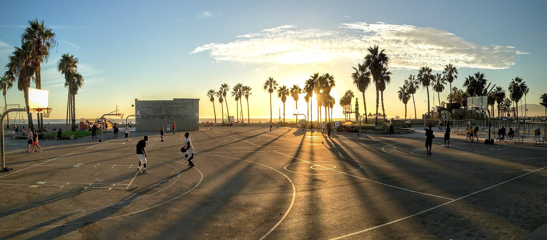 Joueurs de basket sur un terrain en plein air au coucher du soleil